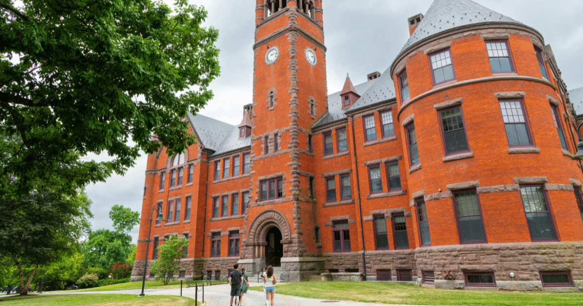 Historic red-brick campus hall with a clock tower and students walking the lawn during a Parents Weekend visit